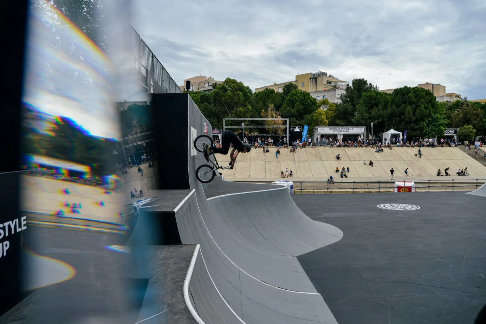 Figure aérienne en BMX sur une rampe de skatepark, ambiance de contest extérieur.