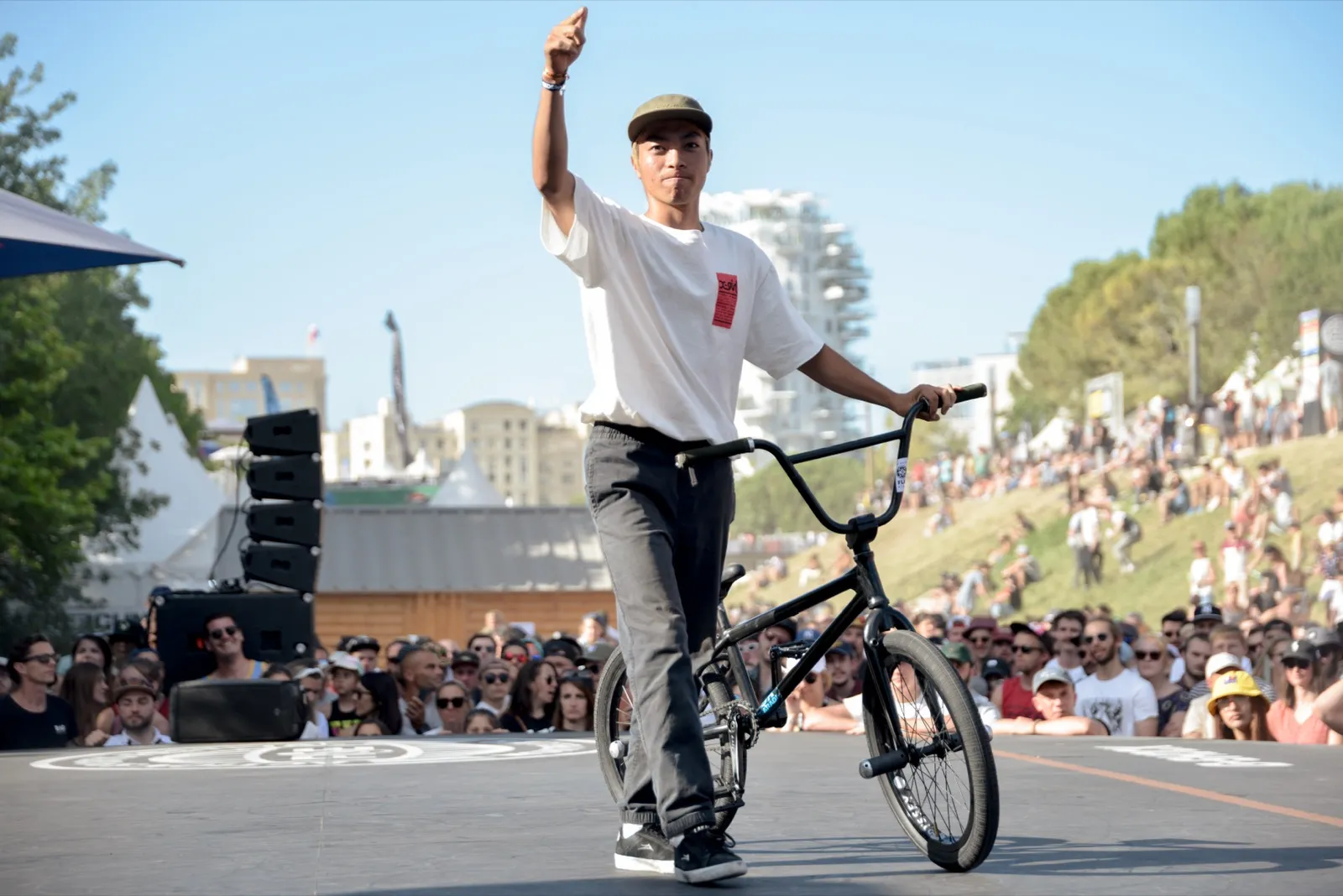 Rider BMX saluant la foule, en équilibre sur son vélo, scène de fin de run.