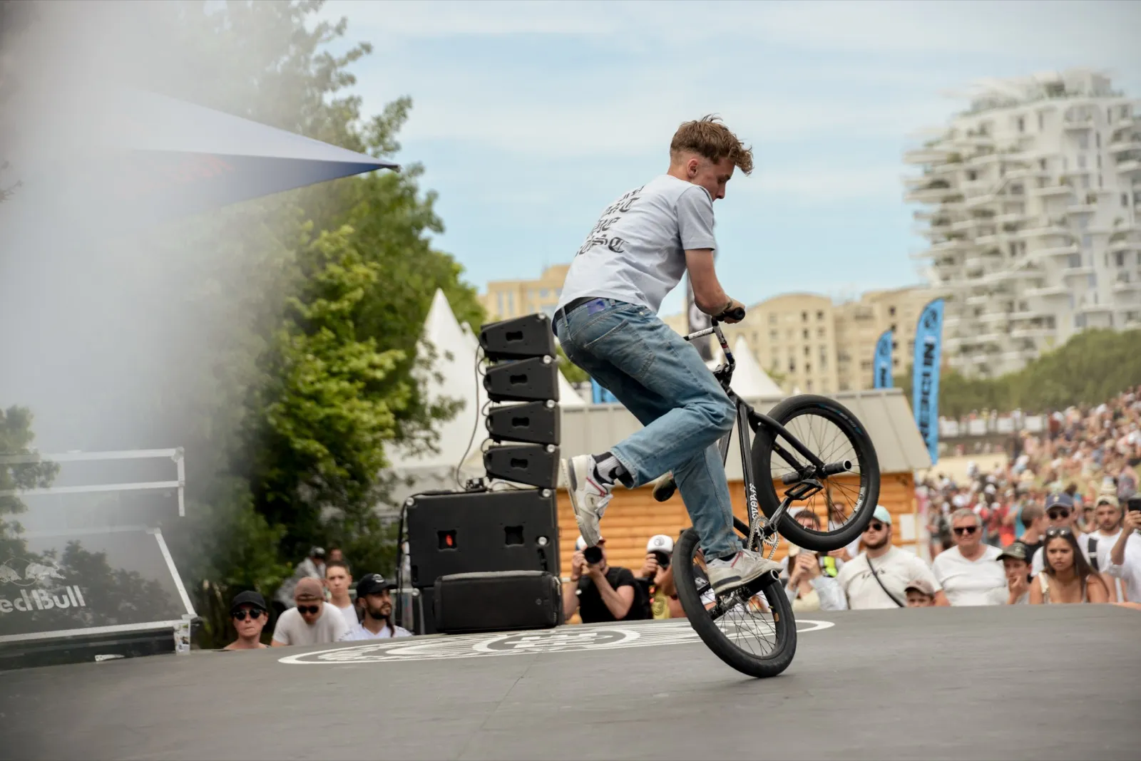 Figure de flat BMX en pleine démonstration, foule en arrière-plan.