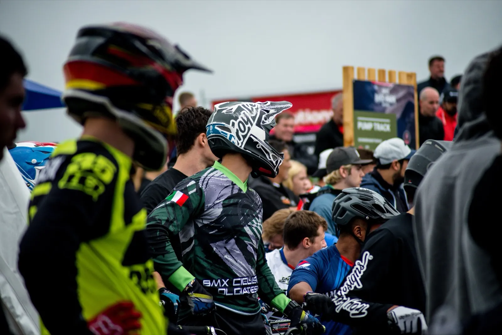 Groupe de riders BMX alignés en tenue complète au départ d’une course, casques et numéros bien visibles.