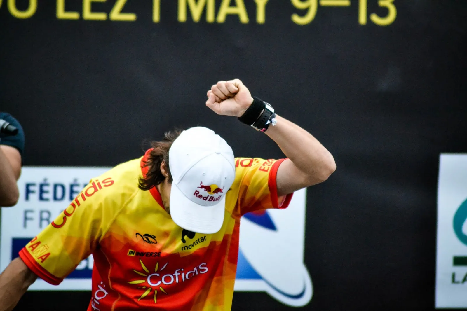 Athlète levant le poing après une performance, maillot jaune et rouge de l’équipe d’Espagne.