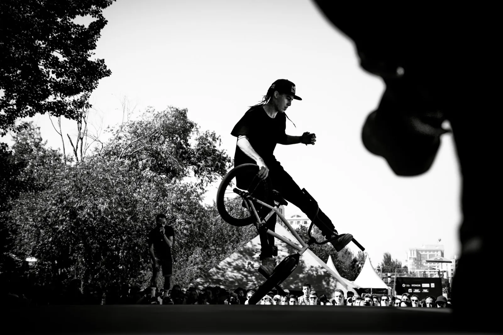 Rider BMX capté en figure aérienne, contre-jour et silhouettes en premier plan.