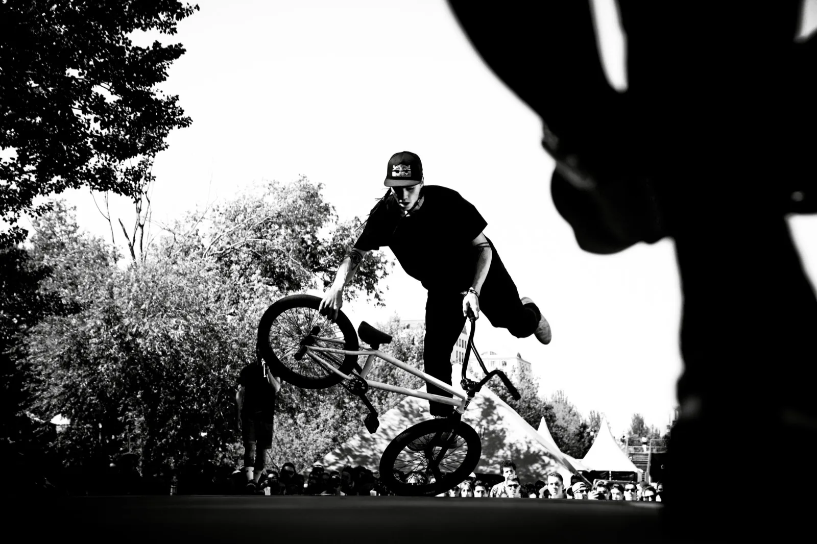 Scène de BMX en pleine manœuvre, captée entre deux silhouettes au premier plan.