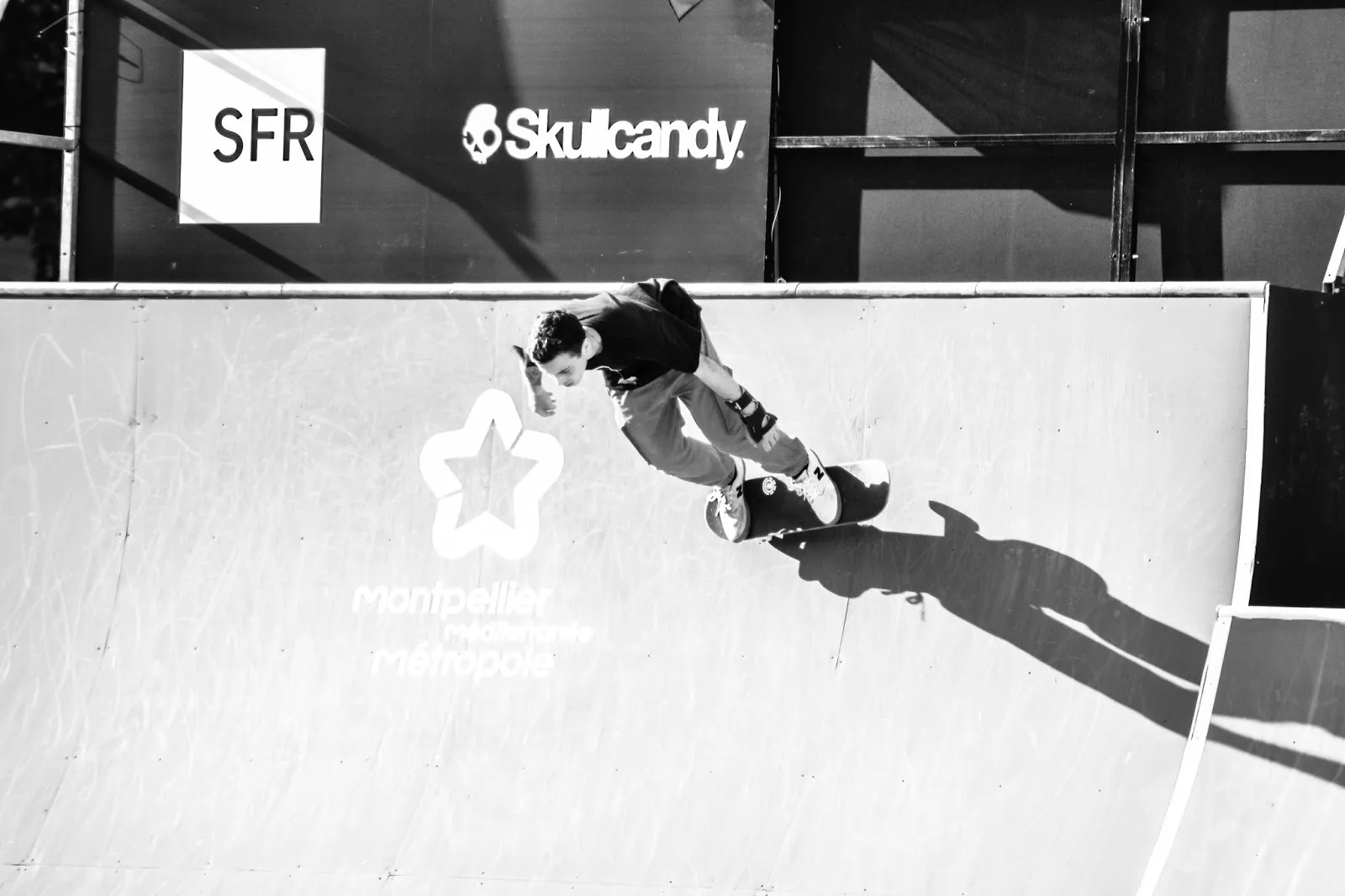 Skateur en descente sur une rampe de compétition, logo Skullcandy visible en fond.