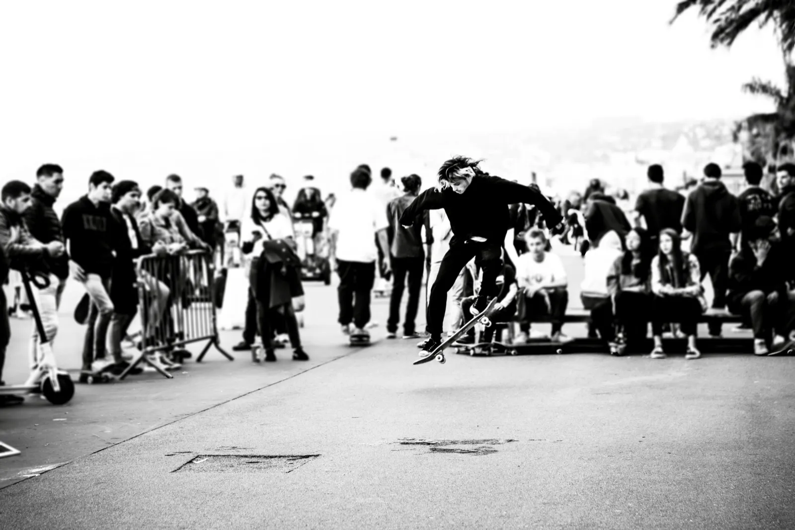 Photo de groupe en noir et blanc autour d’un rider en action au sol, ambiance street session.