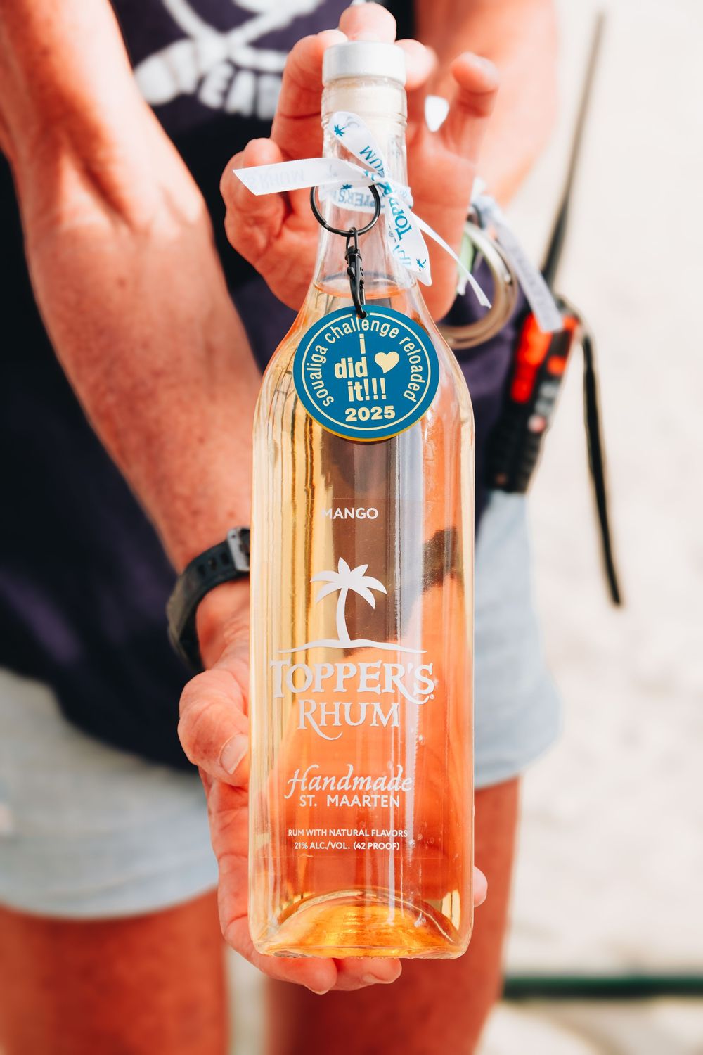 Close-up of hands holding a bottle of Coppers Rum with a palm tree logo and special edition label.
