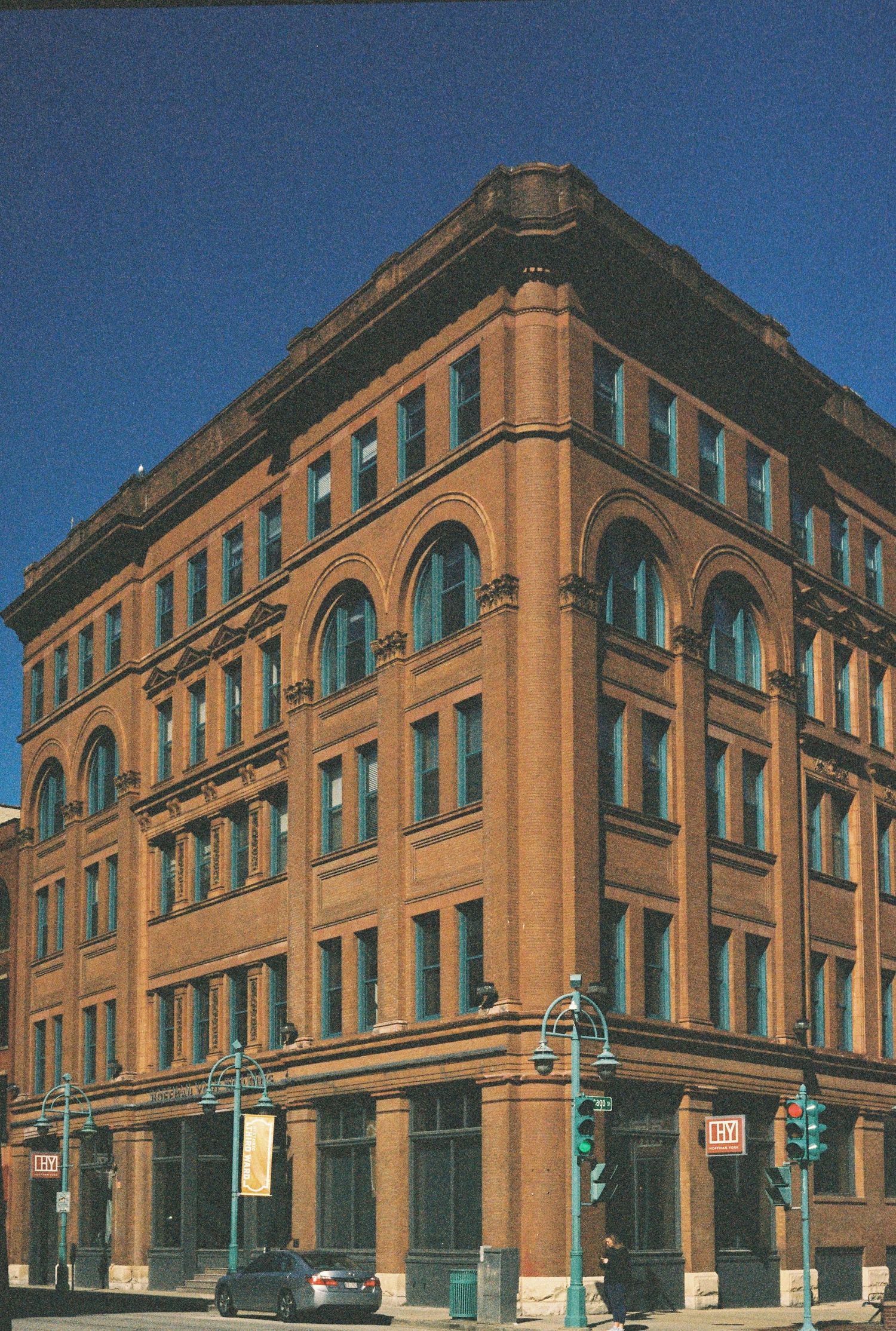 Historic brick building with arched windows and Romanesque architecture on a city corner.