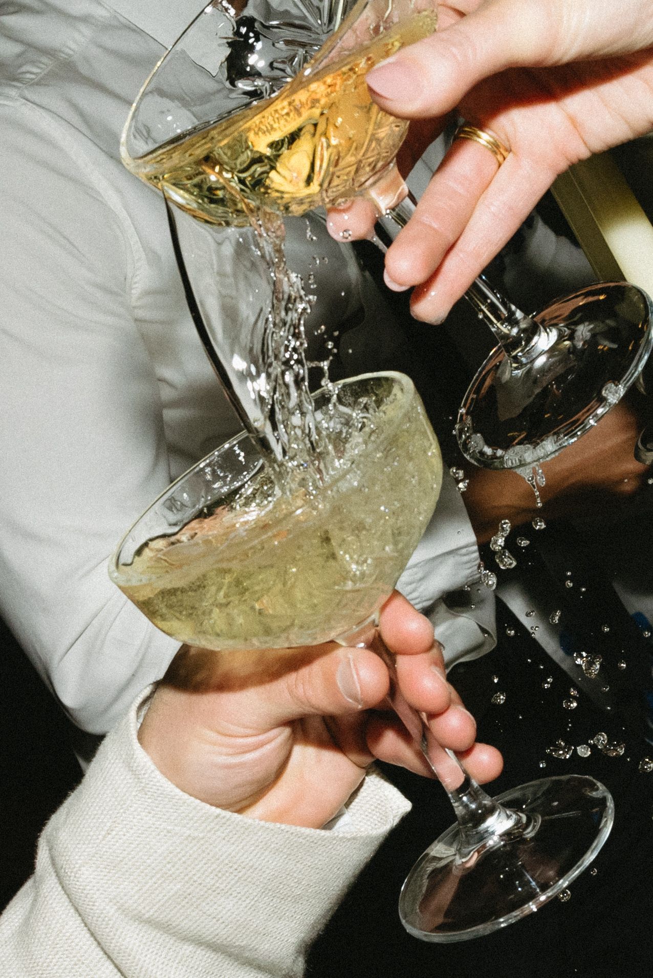 Champagne being poured into a coupe glass creating a splashing effect.