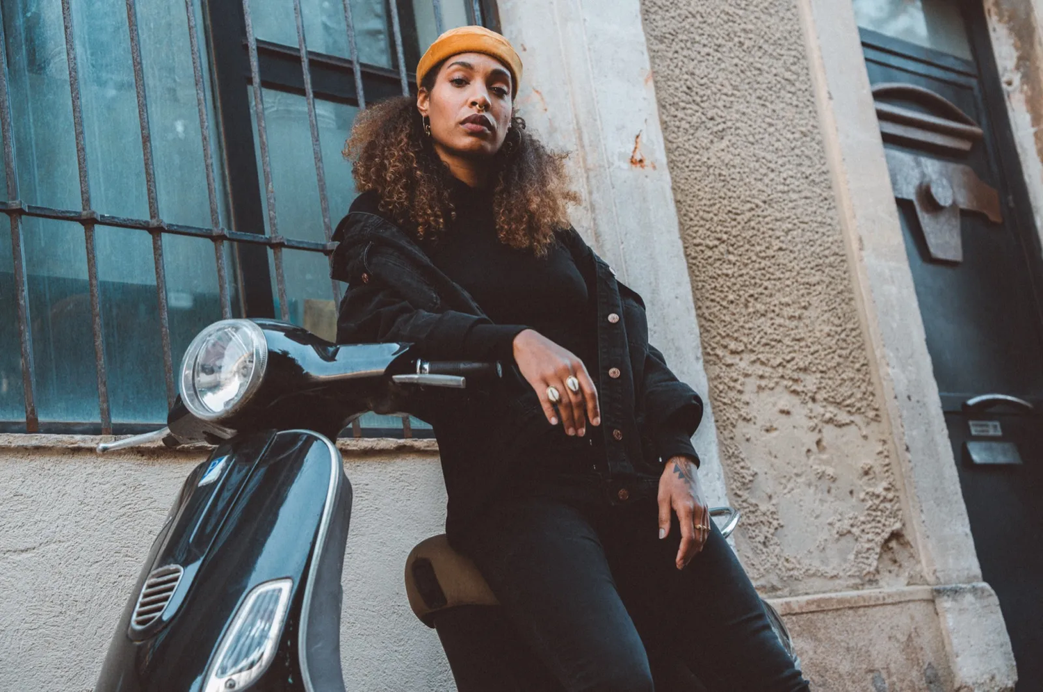 Portrait urbain d’une jeune femme posée sur un scooter, en extérieur.