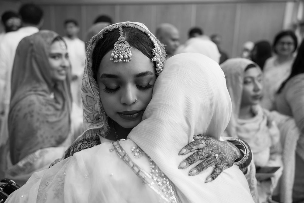 An emotional moment during a traditional South Asian wedding ceremony captured in black and white.