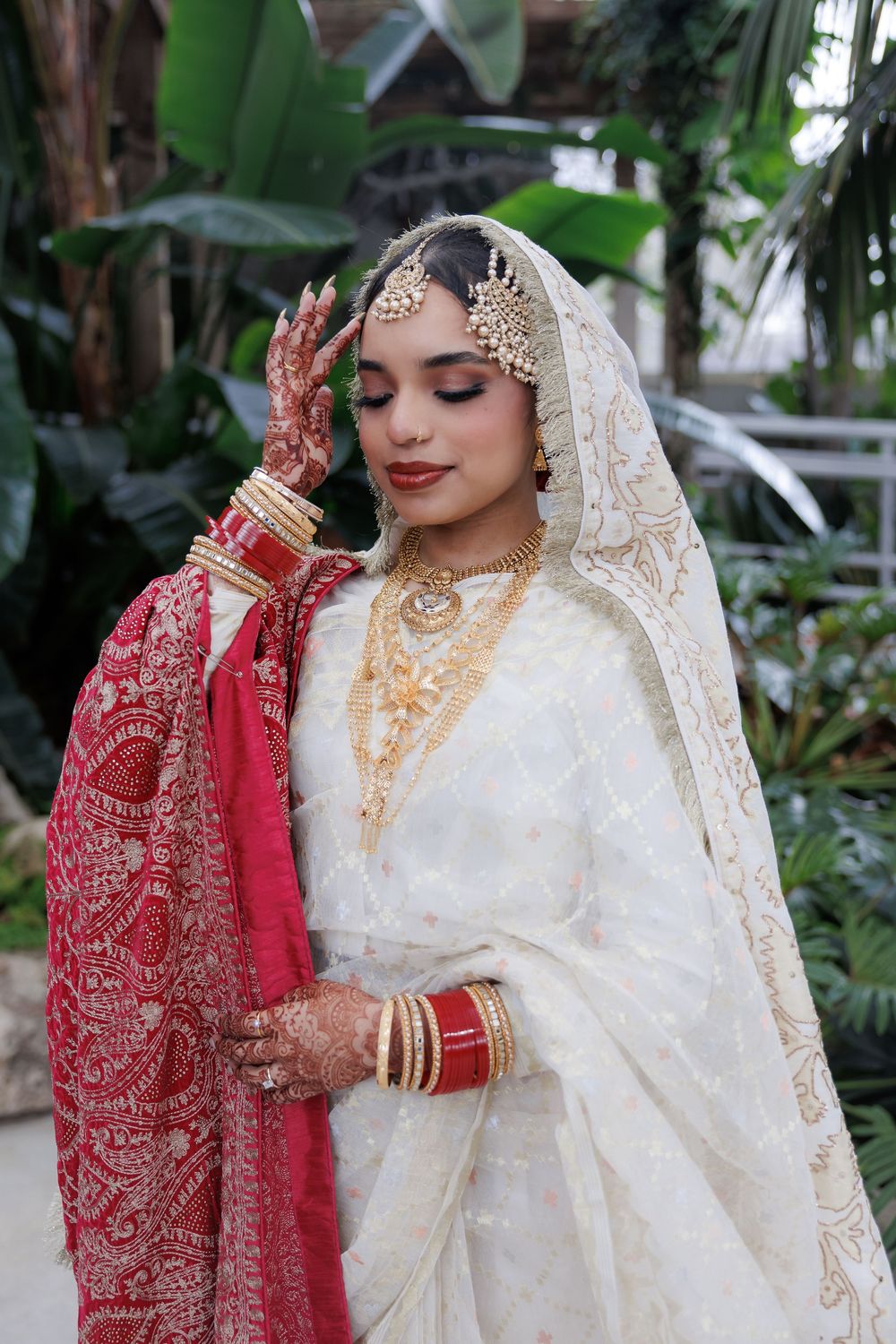 Traditional bridal attire with intricate gold jewelry and delicate white lace details.