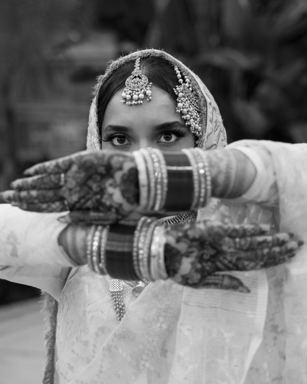 Close-up details of intricate henna designs and jewelry on hands adorned with traditional bridal bangles.