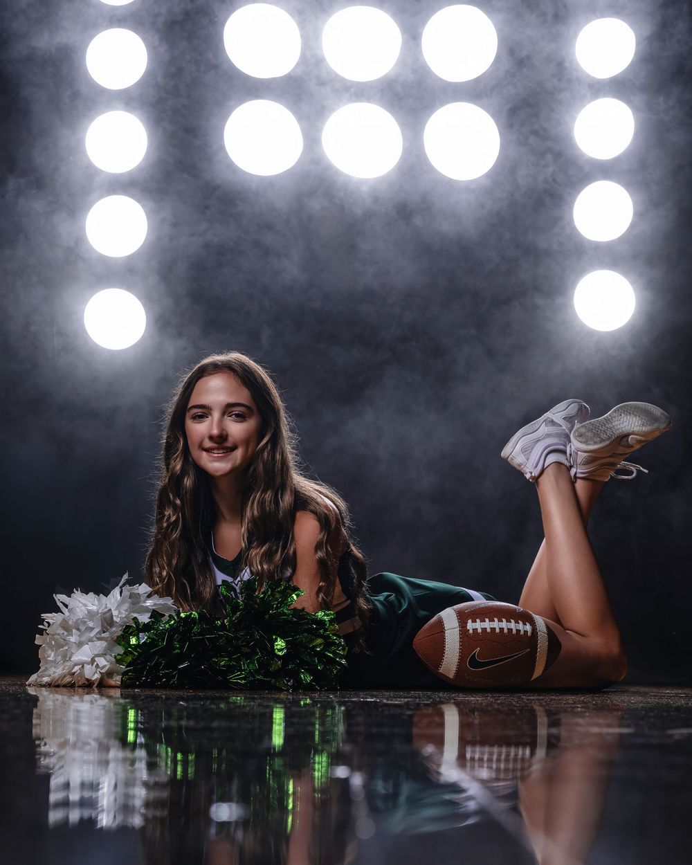 A glamorous sports-themed photo series with dramatic lighting features cheerleading pom poms and a football on a dark floor.