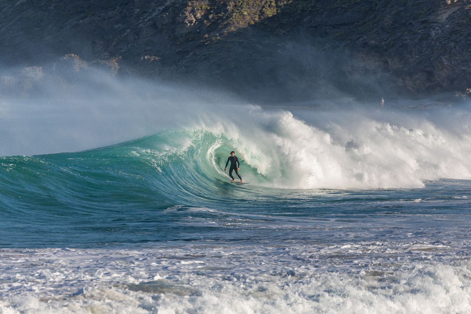 A powerful turquoise ocean wave curls and breaks during sunset creating a perfect barrel formation.