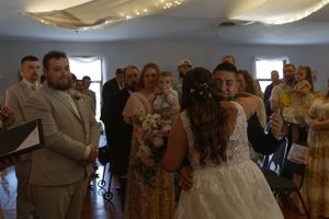 Indoor wedding celebration with guests dancing under decorative lighting.