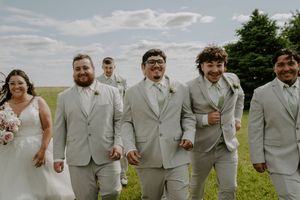 Groomsmen in light gray suits pose casually outdoors.