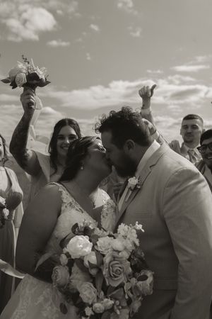 Black and white photo captures joyful celebration moment at outdoor wedding.