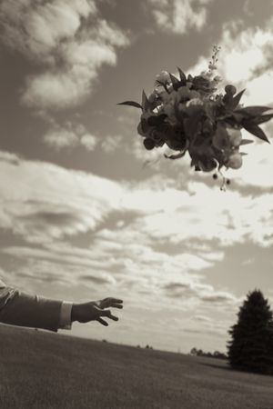 Black and white sequence of bouquet being tossed across dramatic sky.