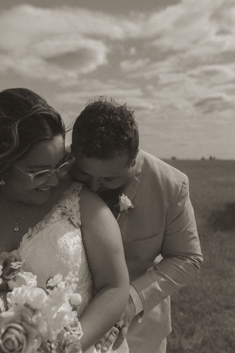 Black and white intimate wedding portraits captured in a field.