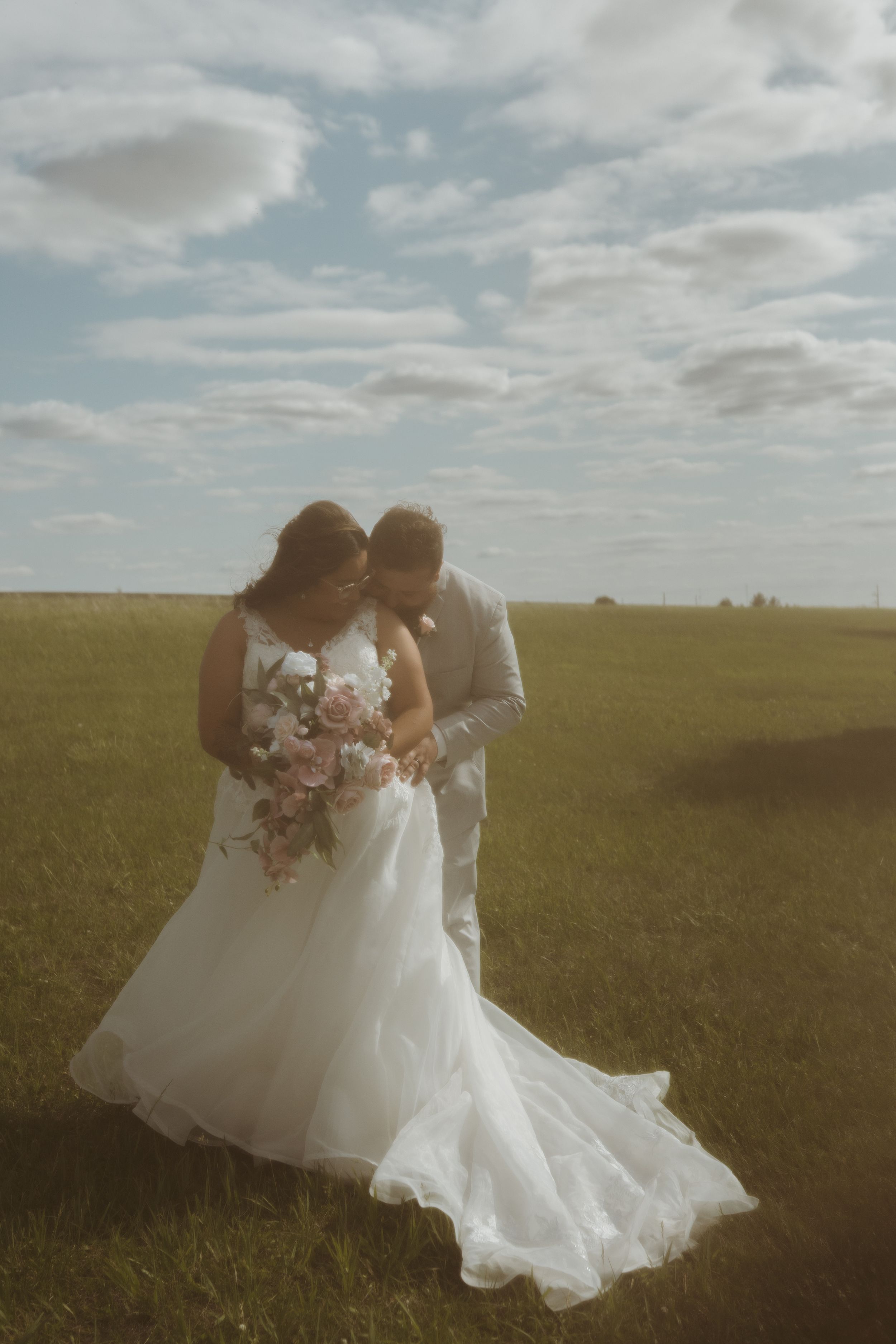 Romantic wedding photos in a sunlit field with flowing white dress.