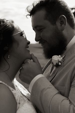 An intimate black and white portrait of newlyweds sharing a romantic moment.