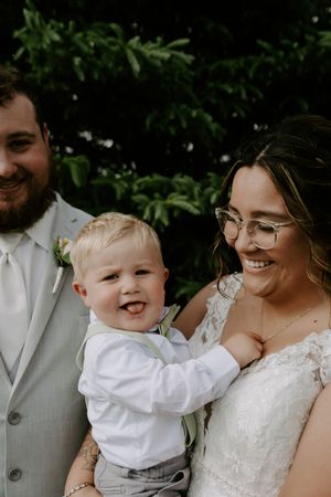 A joyful moment at a wedding with a small child in white dress clothes.