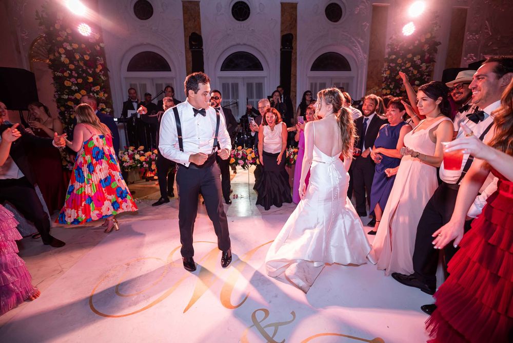 Wedding reception dance floor with the couple performing their first dance under pink lighting at an elegant venue.