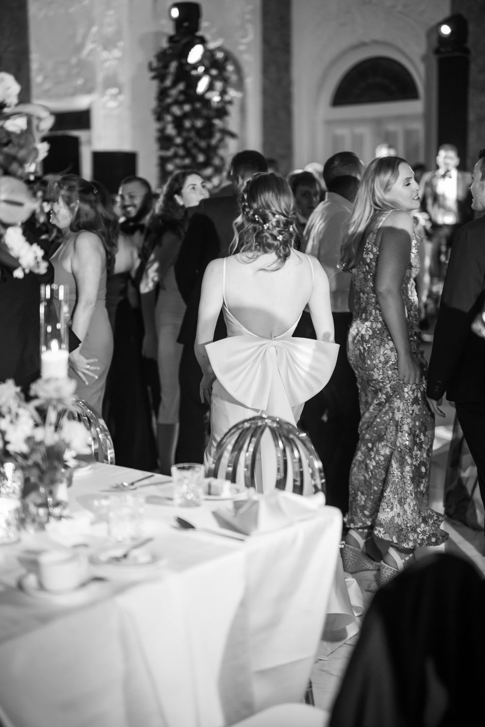 A formal reception gathering with guests around an elegant table setting in black and white.