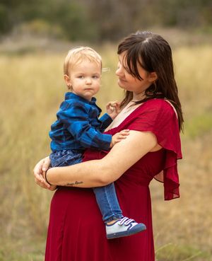 A tender moment between parent and toddler wearing matching red and blue outfits in a field.