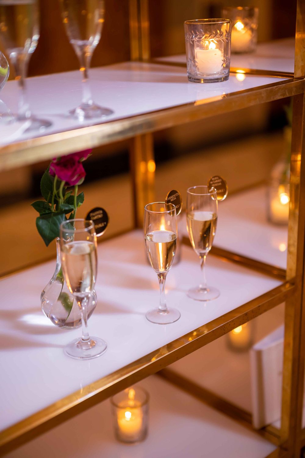 Champagne flutes and red roses decorate elegant gold shelving with romantic candlelight glowing in glass votives.