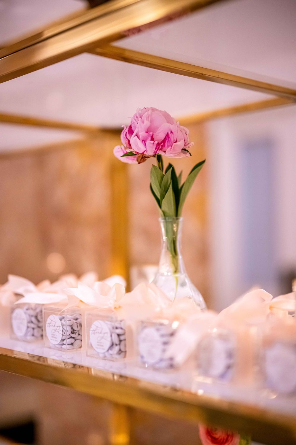 Pink carnations in a glass vase sit atop elegant place settings for a formal dining event.