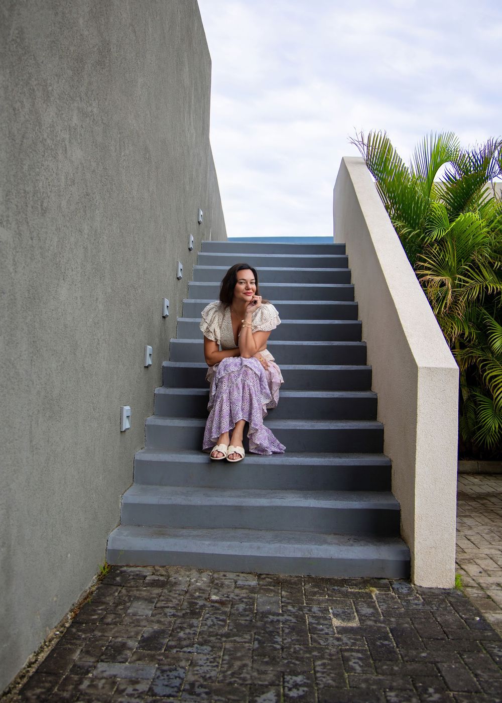 Four sequential photos showing a figure sitting on outdoor concrete steps with palm trees in the background. Saint Maarten