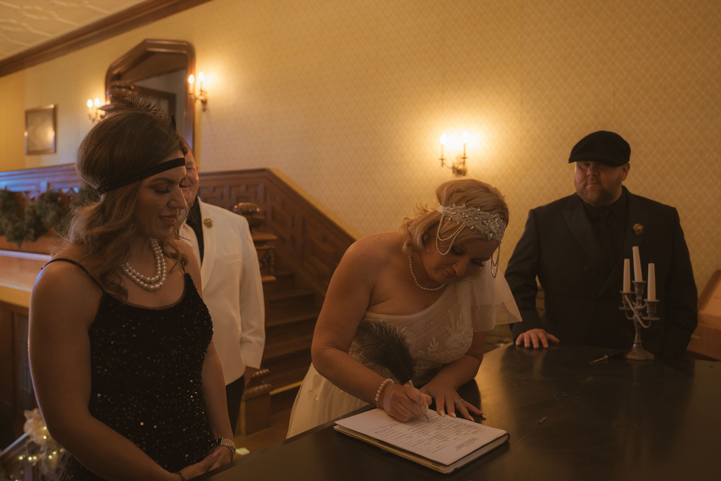 Wedding guests gather in an elegantly lit room with chandelier and warm ambient lighting.