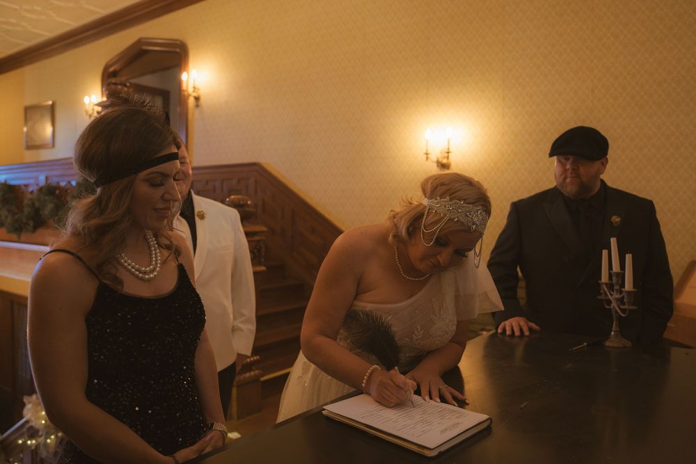 Wedding guests gather in an elegantly lit room with chandelier and warm ambient lighting.