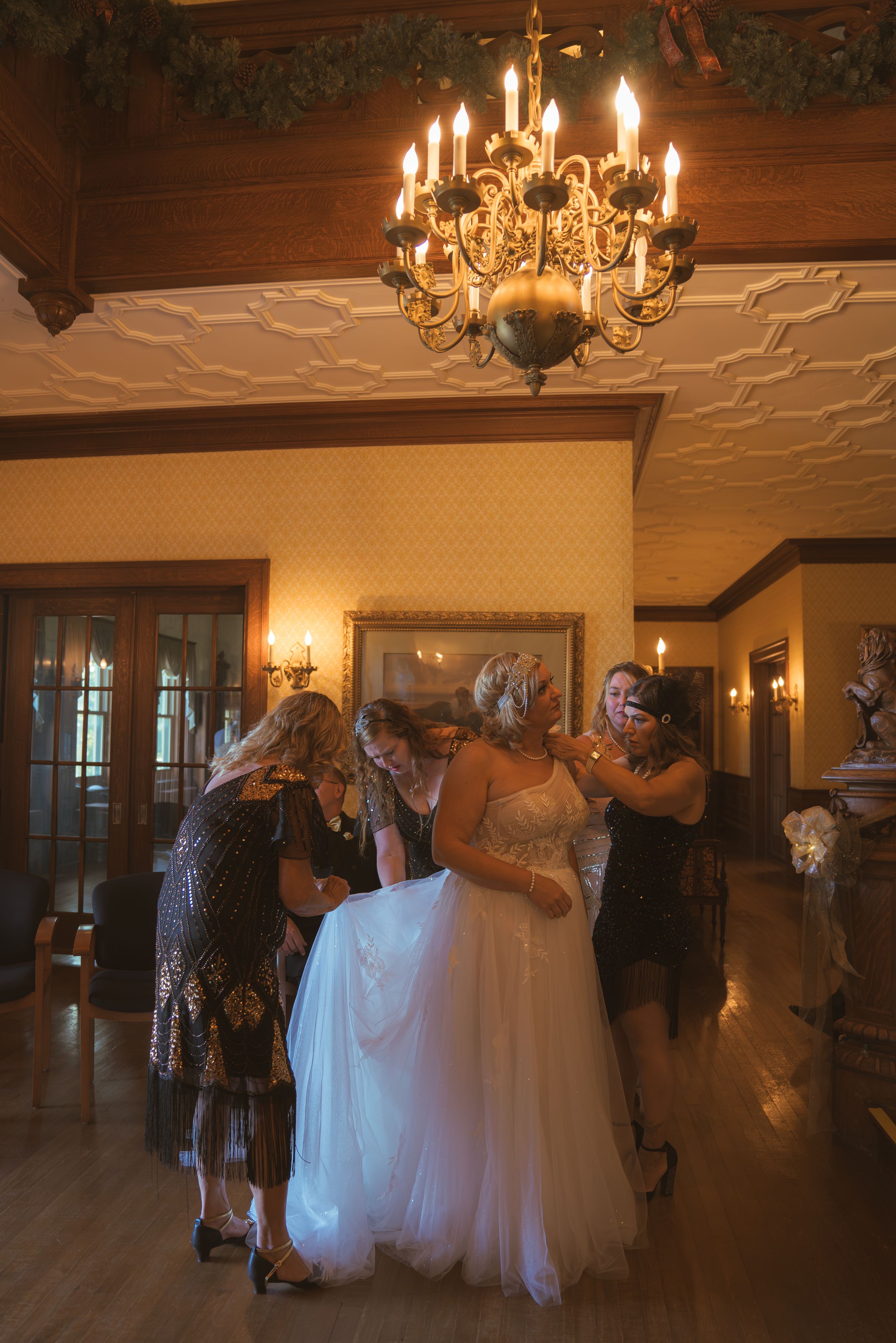 Couples dancing in a grand ballroom under ornate chandeliers at a wedding reception.