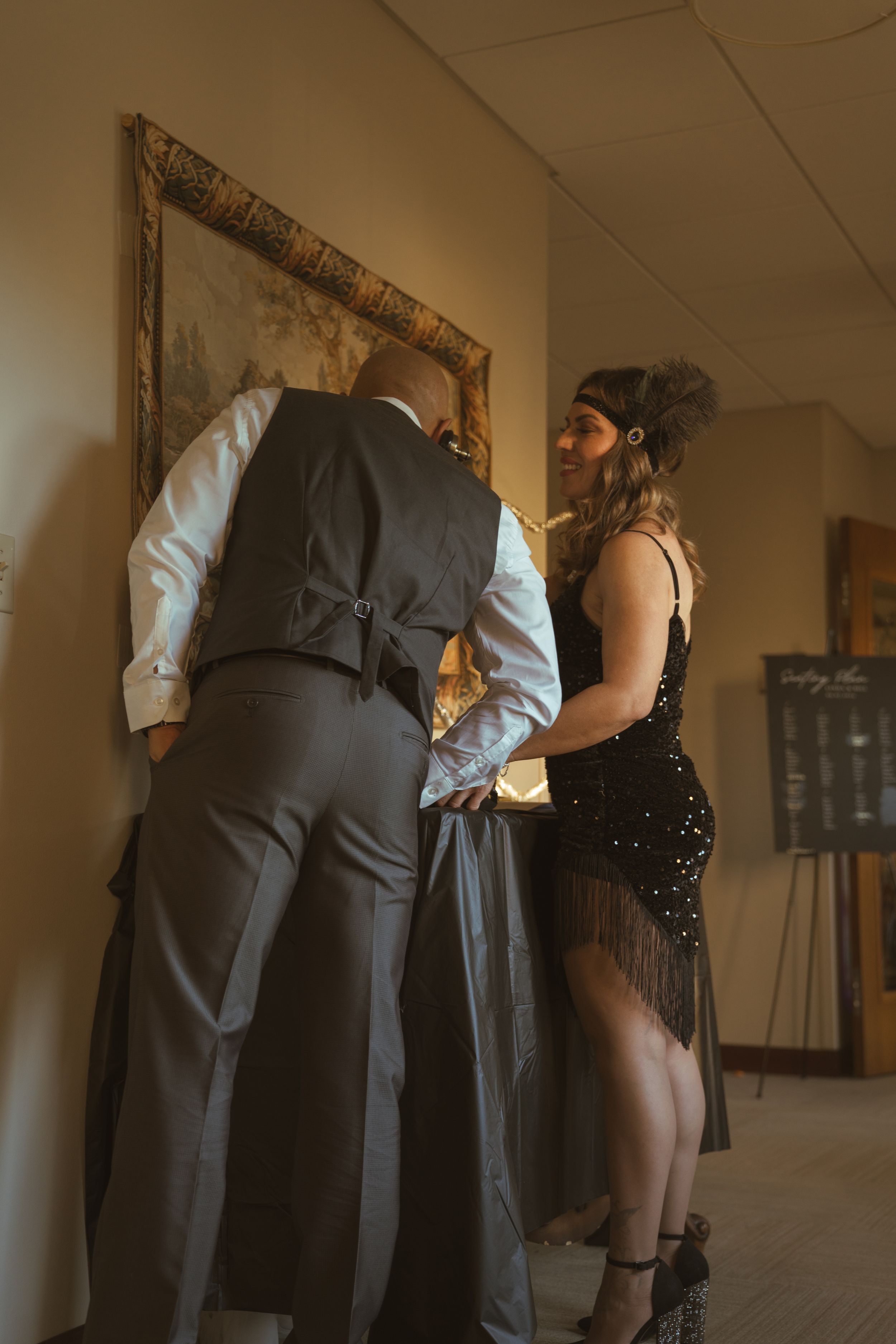 Close-up view of formal attire showing grey vest and black dress details at a wedding.