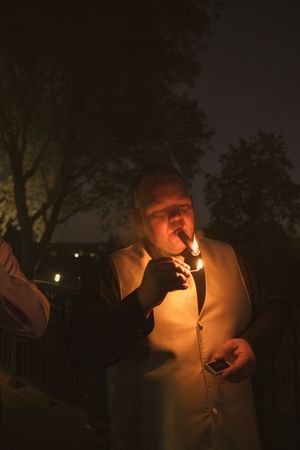 Warm glow of cigar lighting ceremony during evening wedding festivities.
