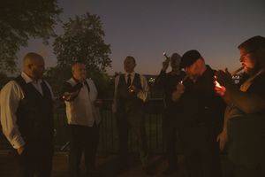 Silhouettes of wedding guests against darkening sky during outdoor reception.