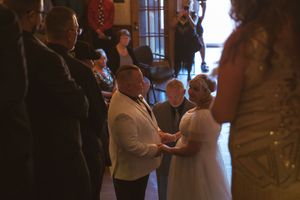 Intimate wedding ceremony taking place in an elegant indoor venue with warm lighting.