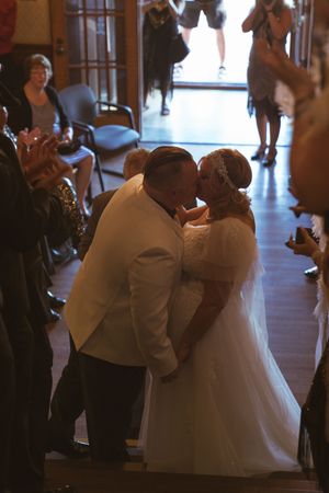 Newlyweds share their first kiss during ceremony while guests capture the moment.