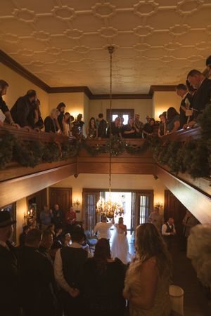 Wedding ceremony viewed from above in an elegant venue with decorative balconies.