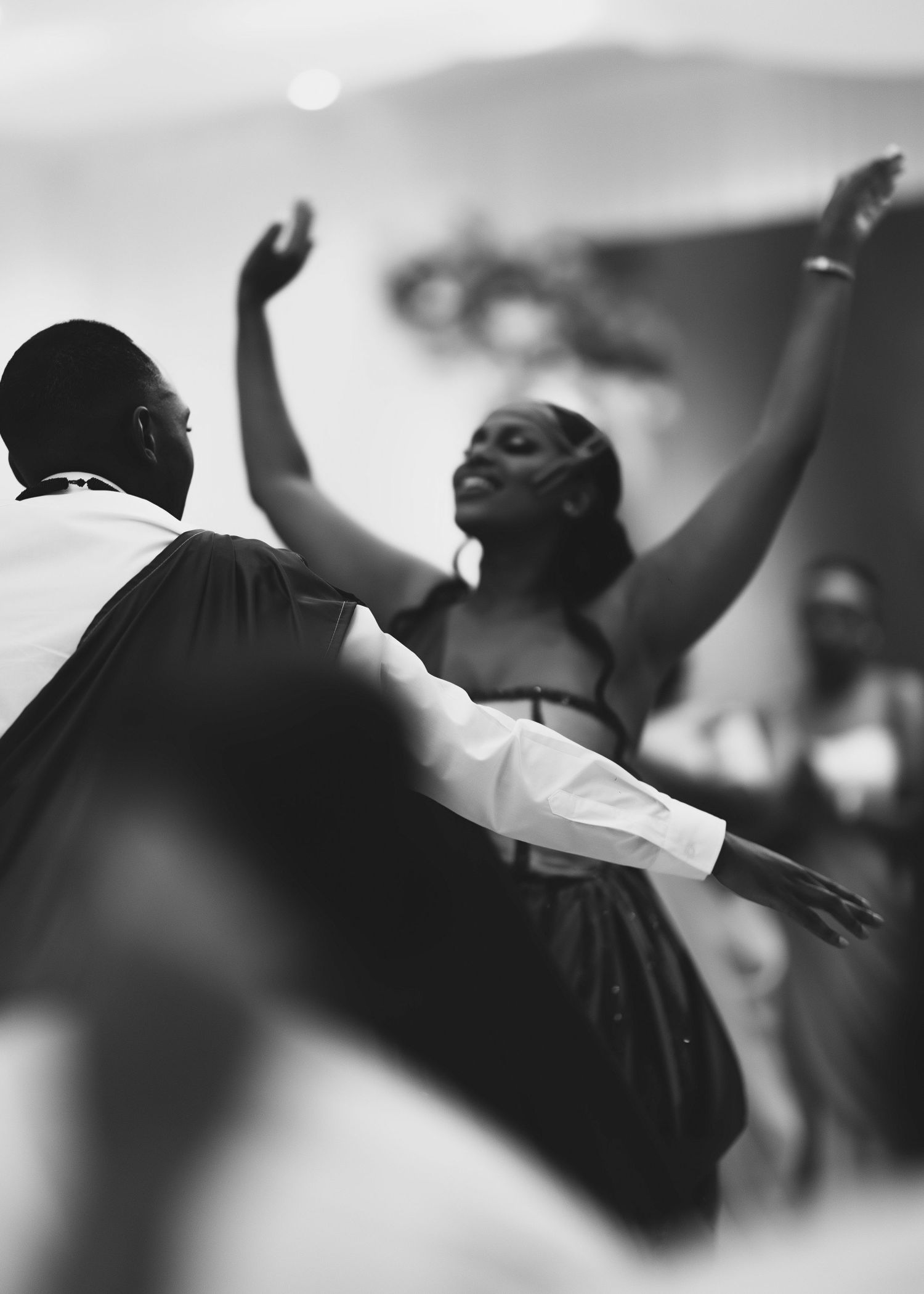 A black and white photo of people dancing with raised arms during a spiritual or worship moment.