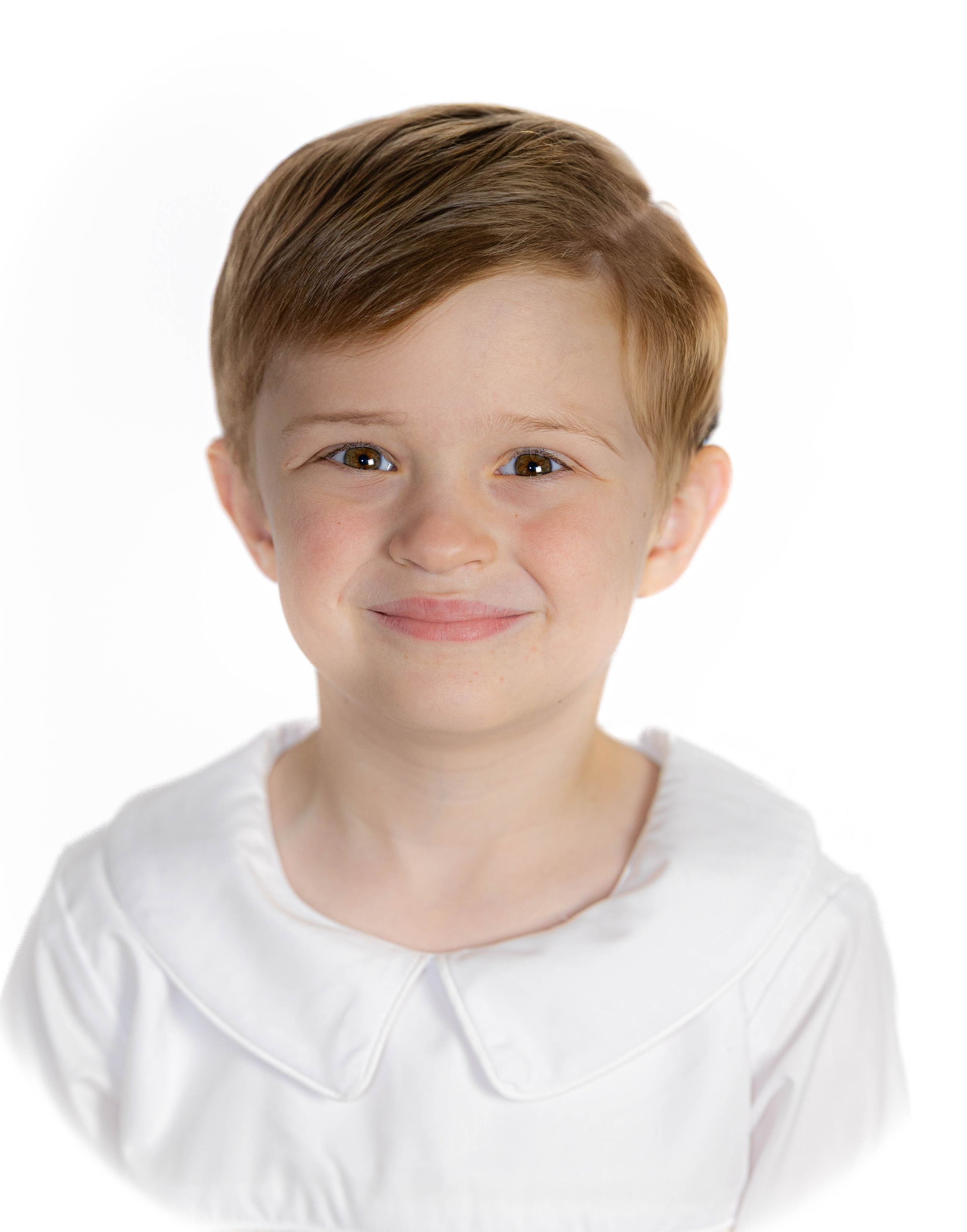 Child in white collared outfit poses against white background.