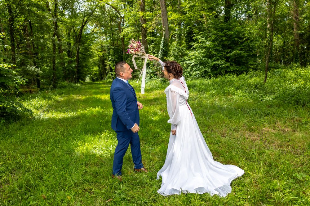 A celebratory wedding scene showing a couple dancing together in a lush green forest setting.