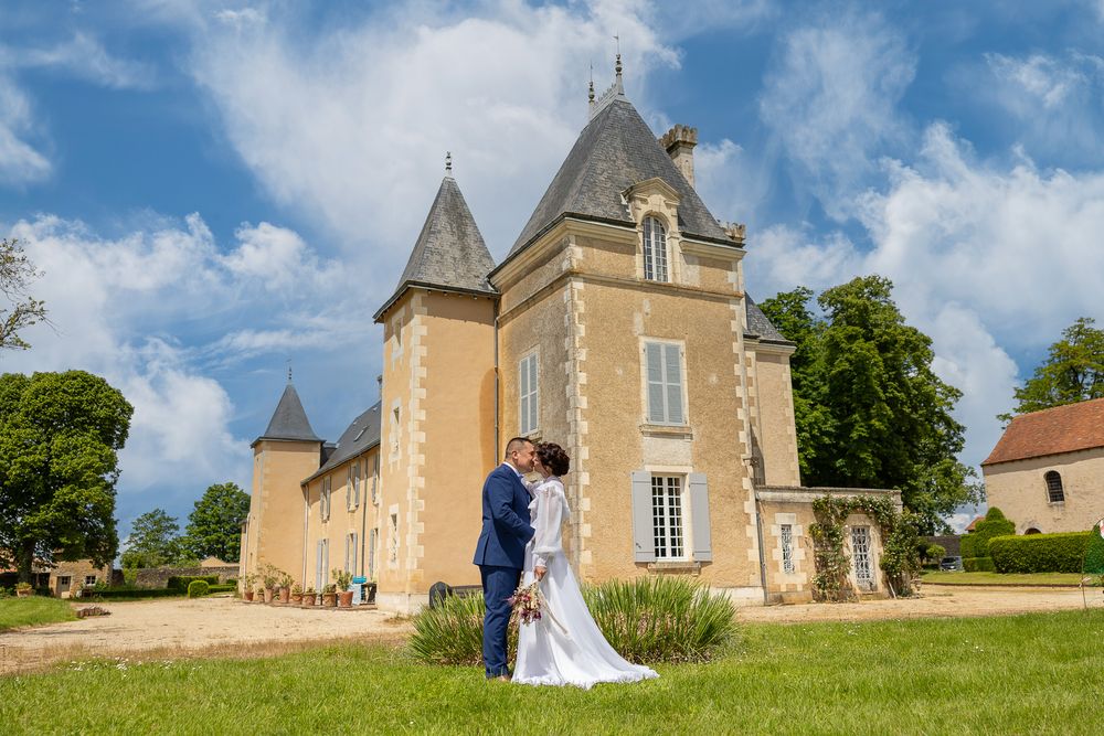 A romantic wedding photo captured in front of a beautiful French chateau with stone turrets.