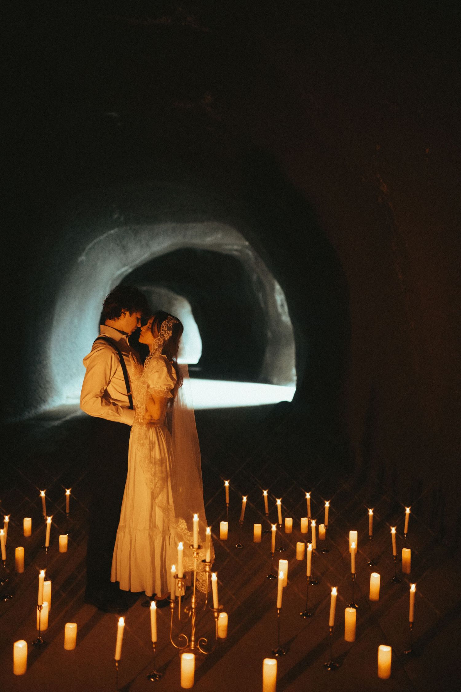 A romantic silhouette of a couple in an intimate moment against a rustic stone wall with dramatic lighting.