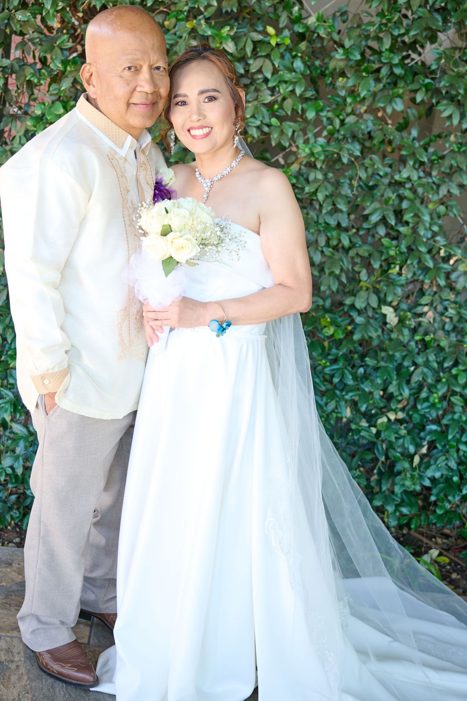 A close-up of a couple at the altar during their wedding ceremony with JHS religious symbol visible.