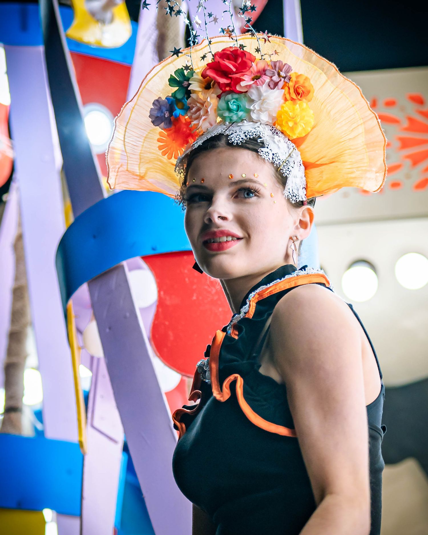 Performer wearing colorful headdress with flowers at festive carnival celebration.