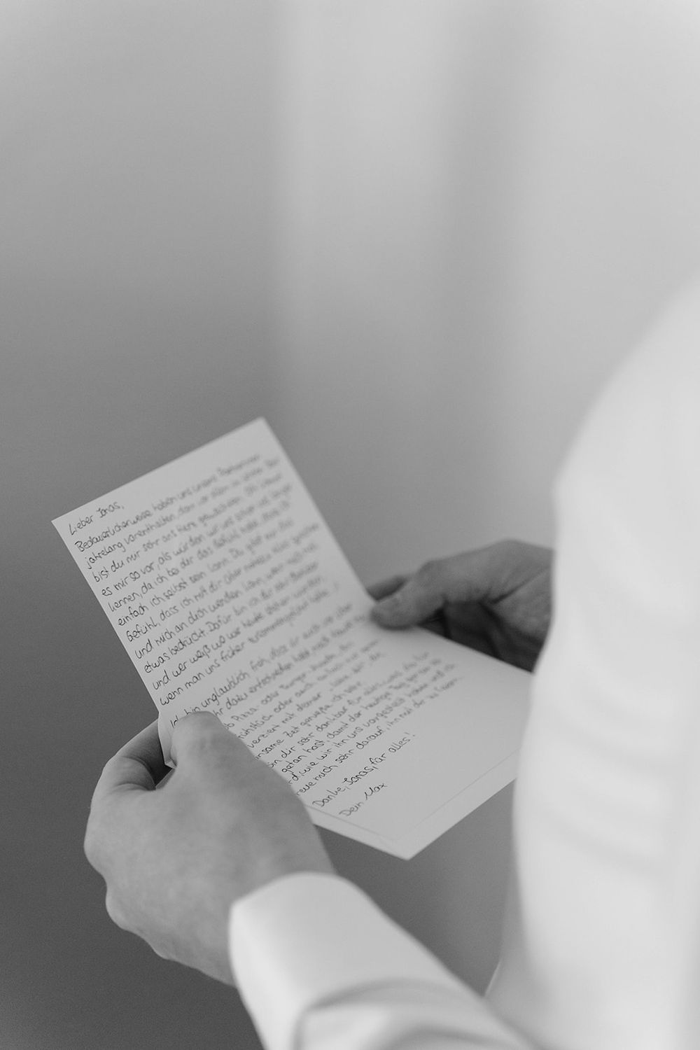 Hands holding a handwritten letter or note against a light background.
