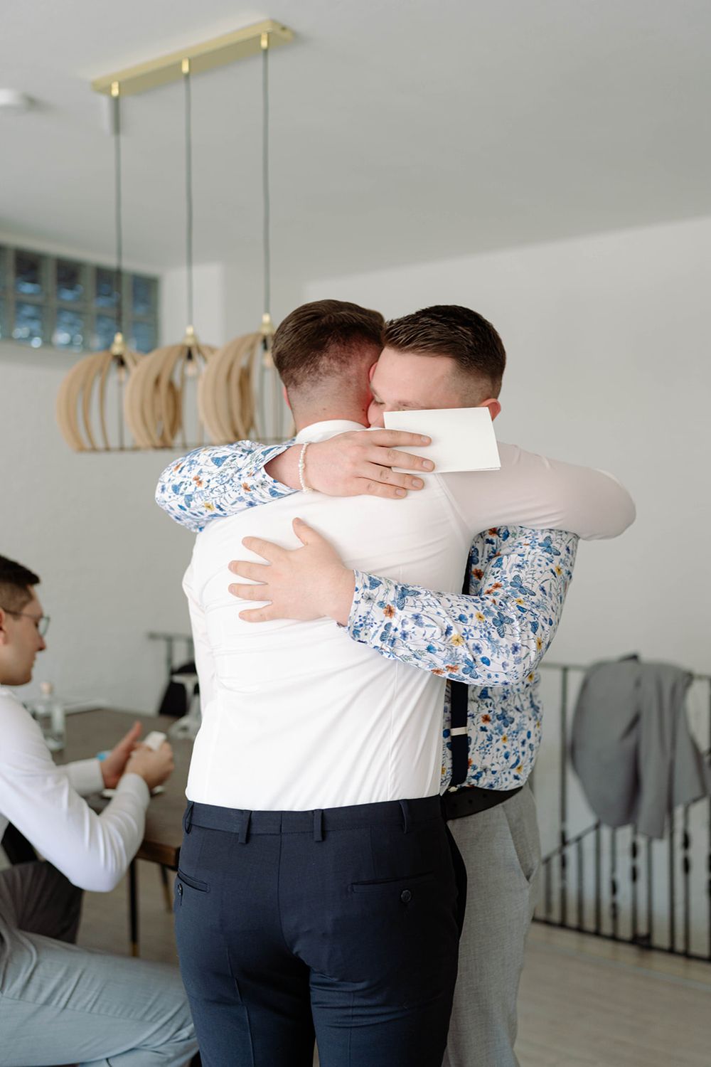 Two people hugging in a bright modern room with pendant lights.